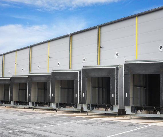 Warehouse loading docks on a sunny day. Open gates of an industrial warehouse. Storehouse doors in a row. Distribution warehouse with open doors.